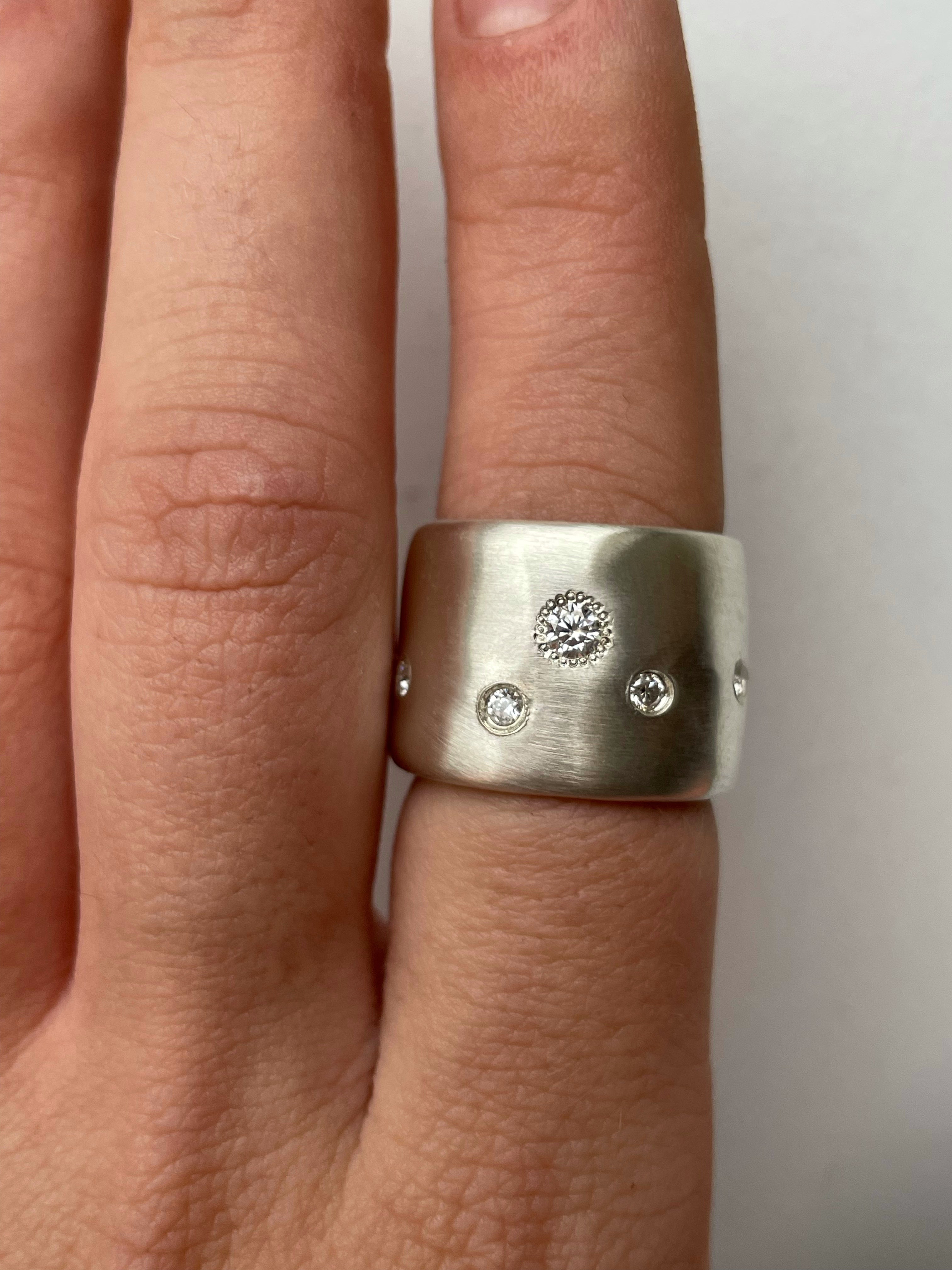Silver ring with embedded moissanite on a finger