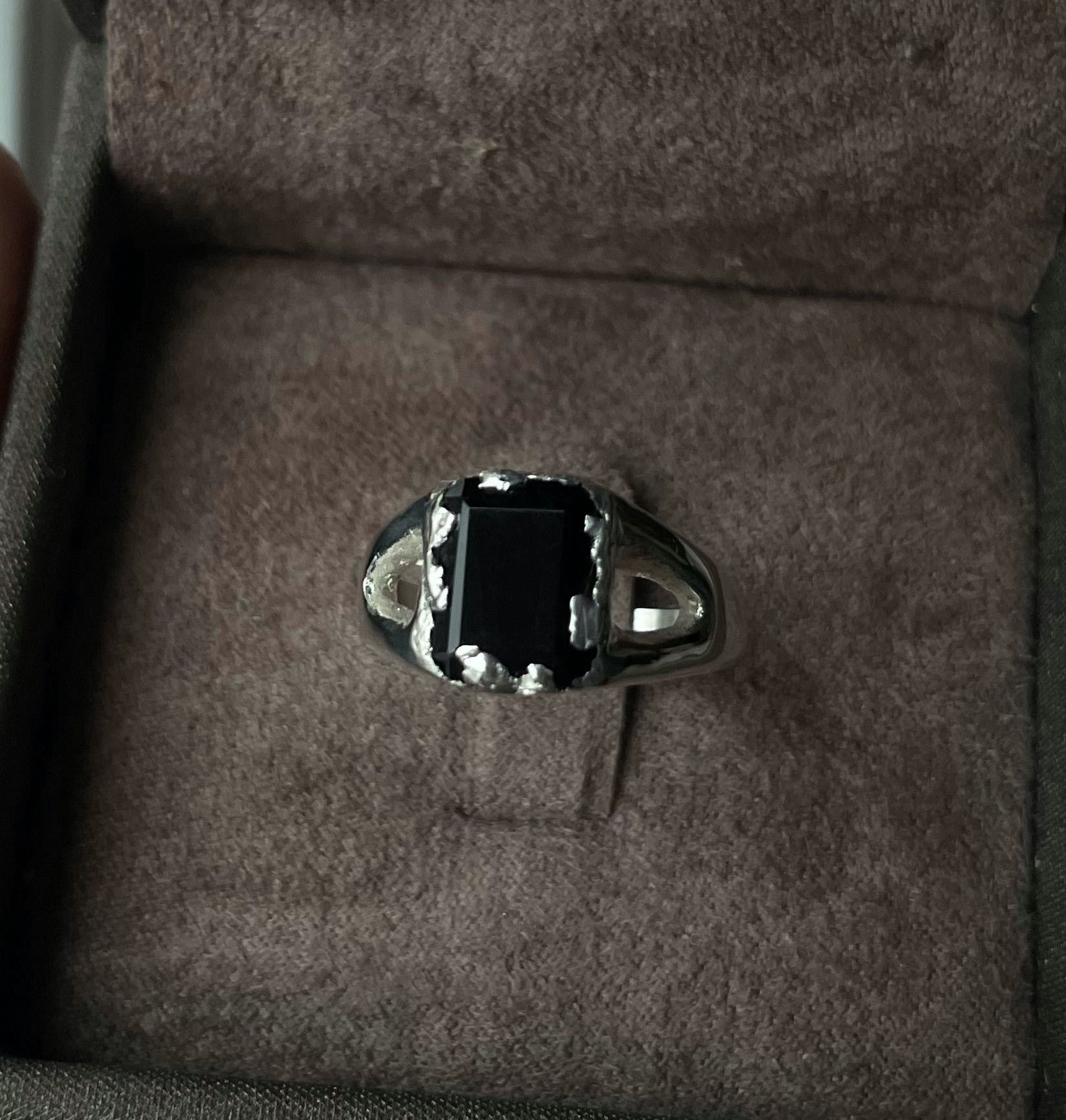 Unisex silver ring with a black onyx on a brown fabric