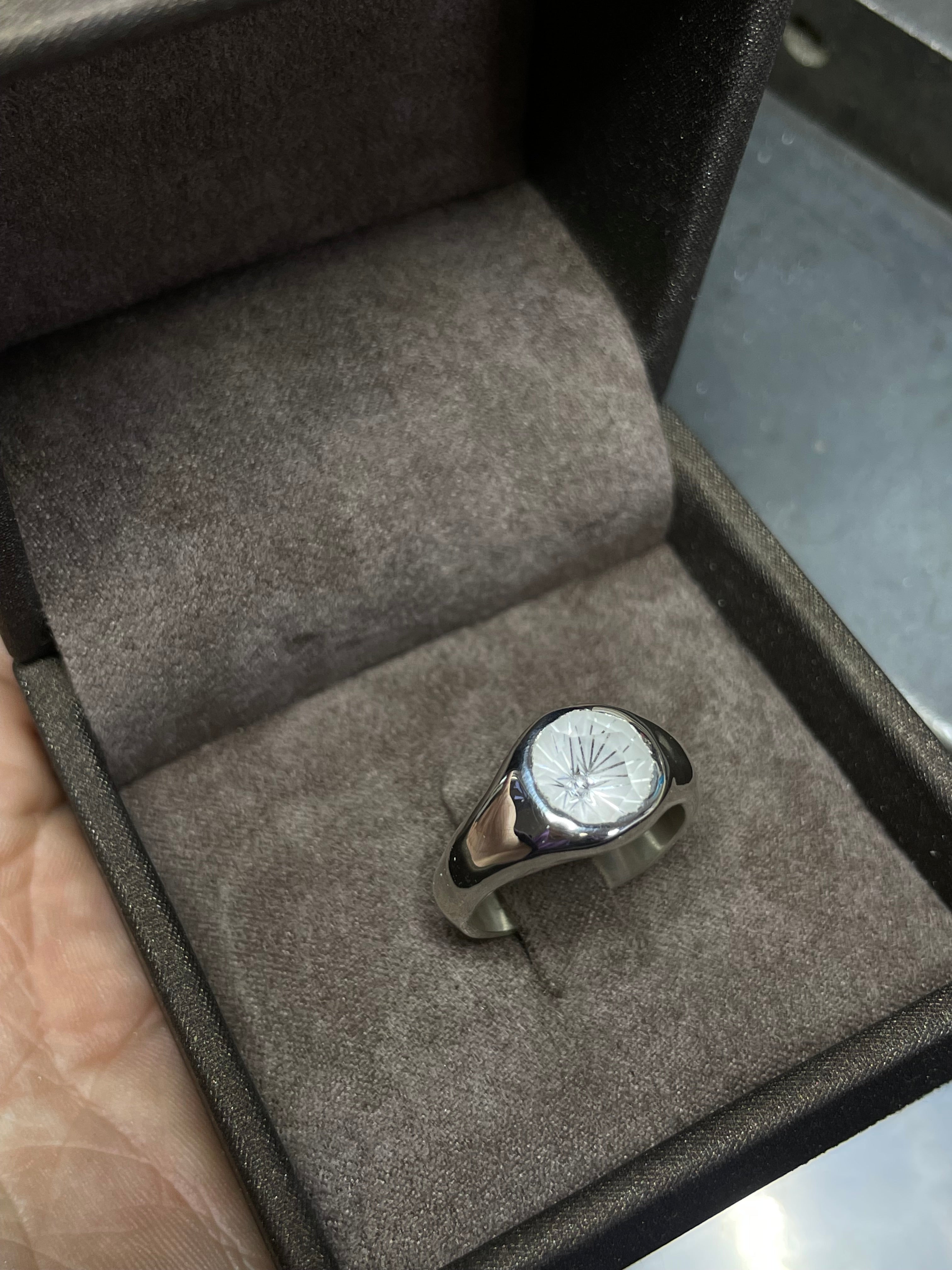 Silver ring with a rock crystal on a gray textured surface
