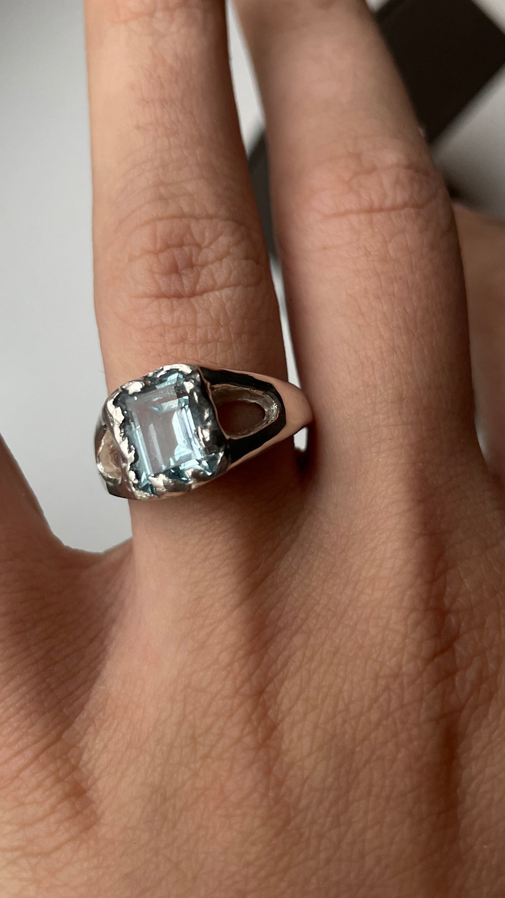 Close-up of a hand wearing a silver ring with a large sky topaz .
