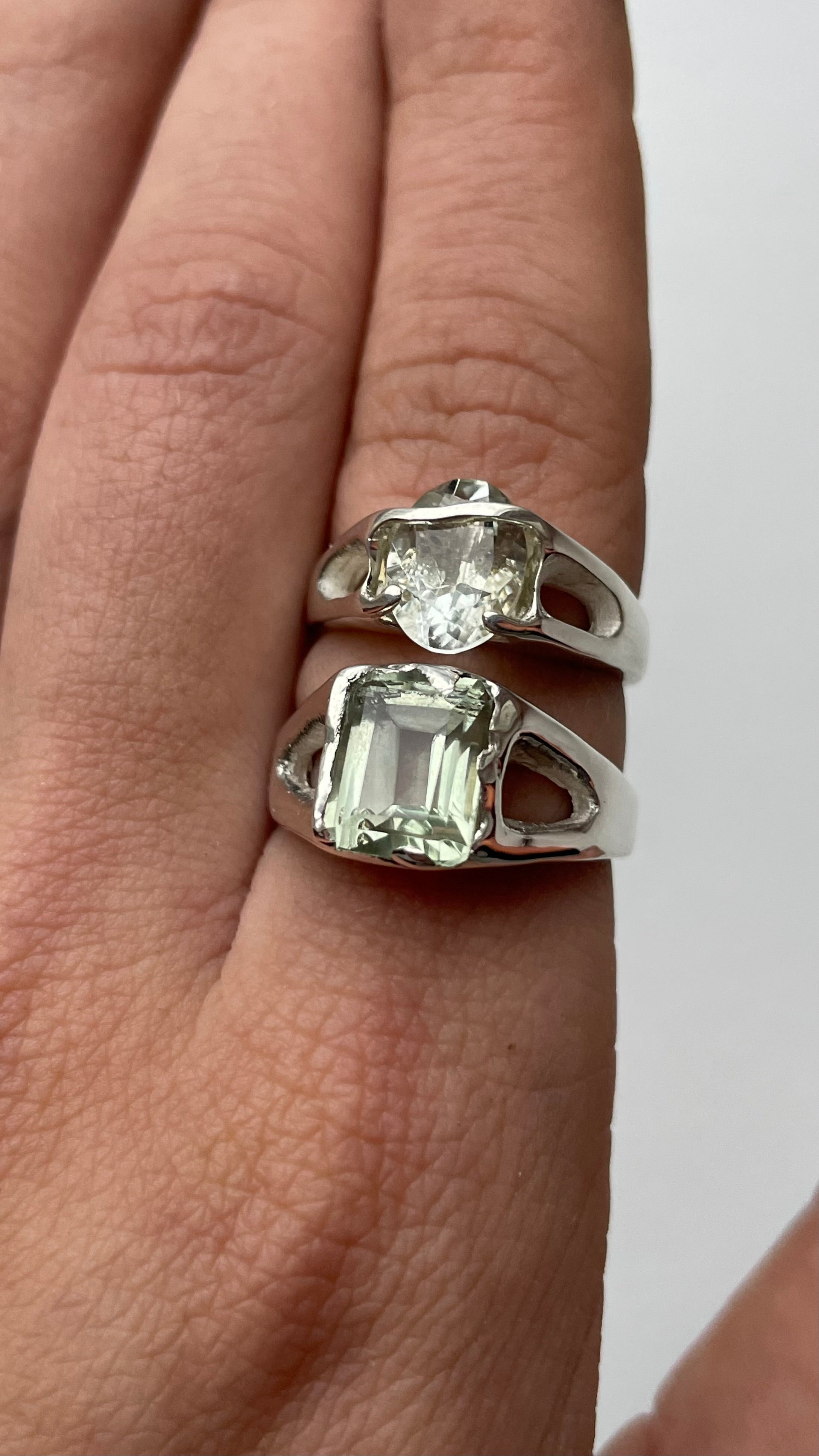 Silver ring with green amethyst on a finger against a white background