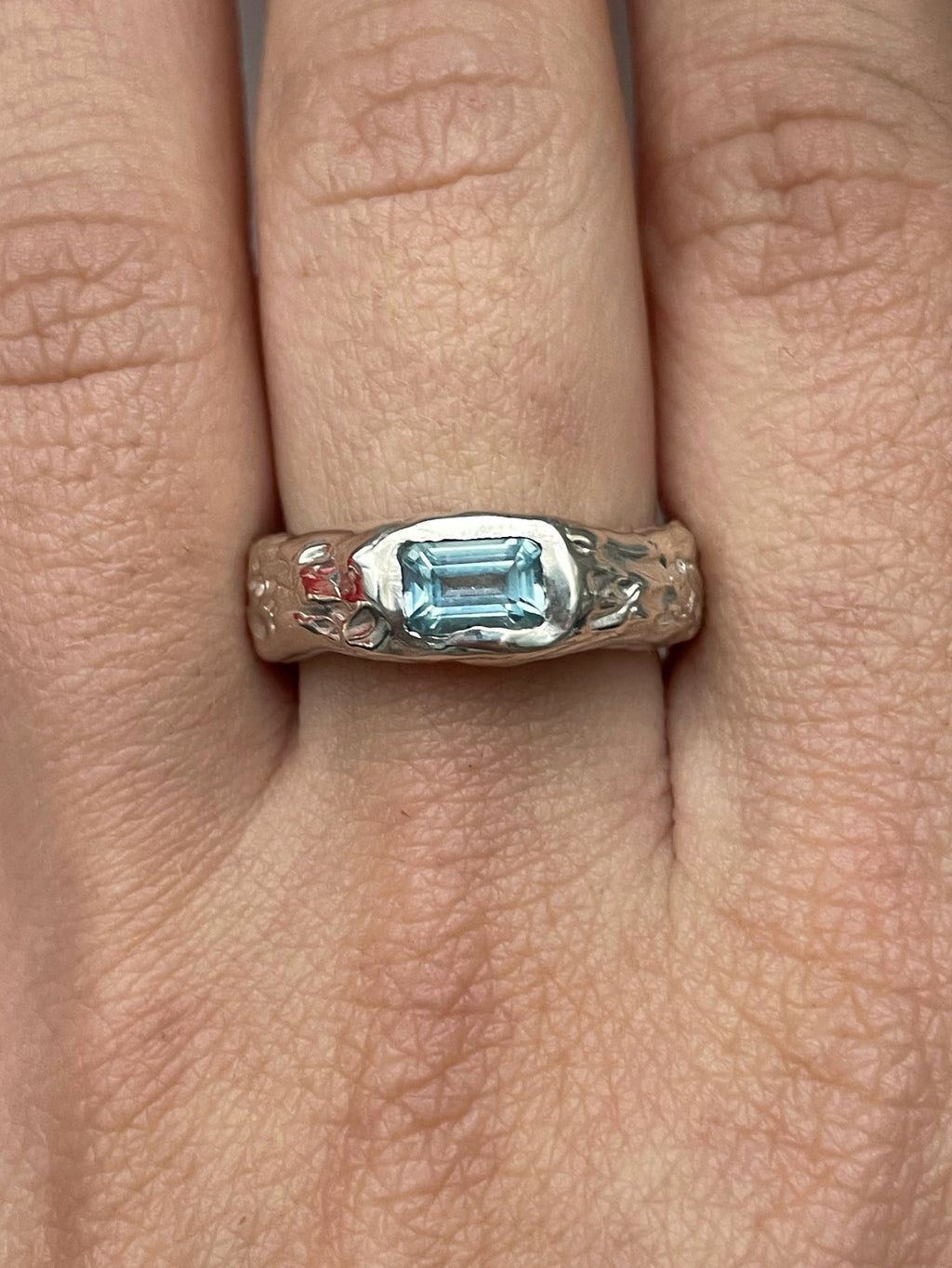 Silver handmade ring with a blue sky topaz on a finger