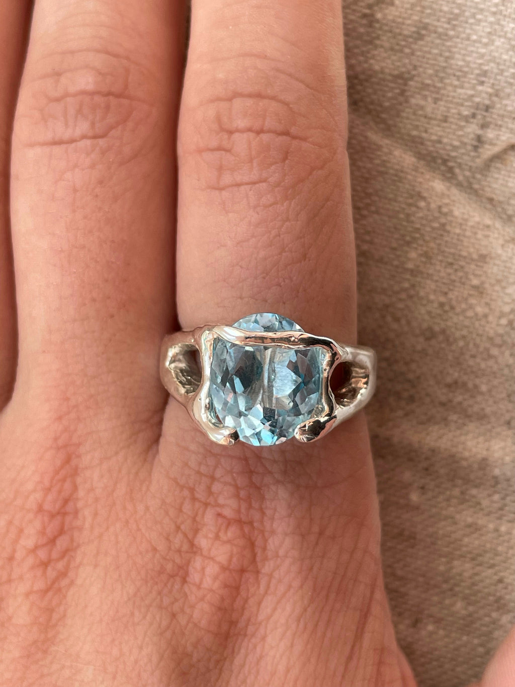 Bespoke silver ring with topaz on finger.