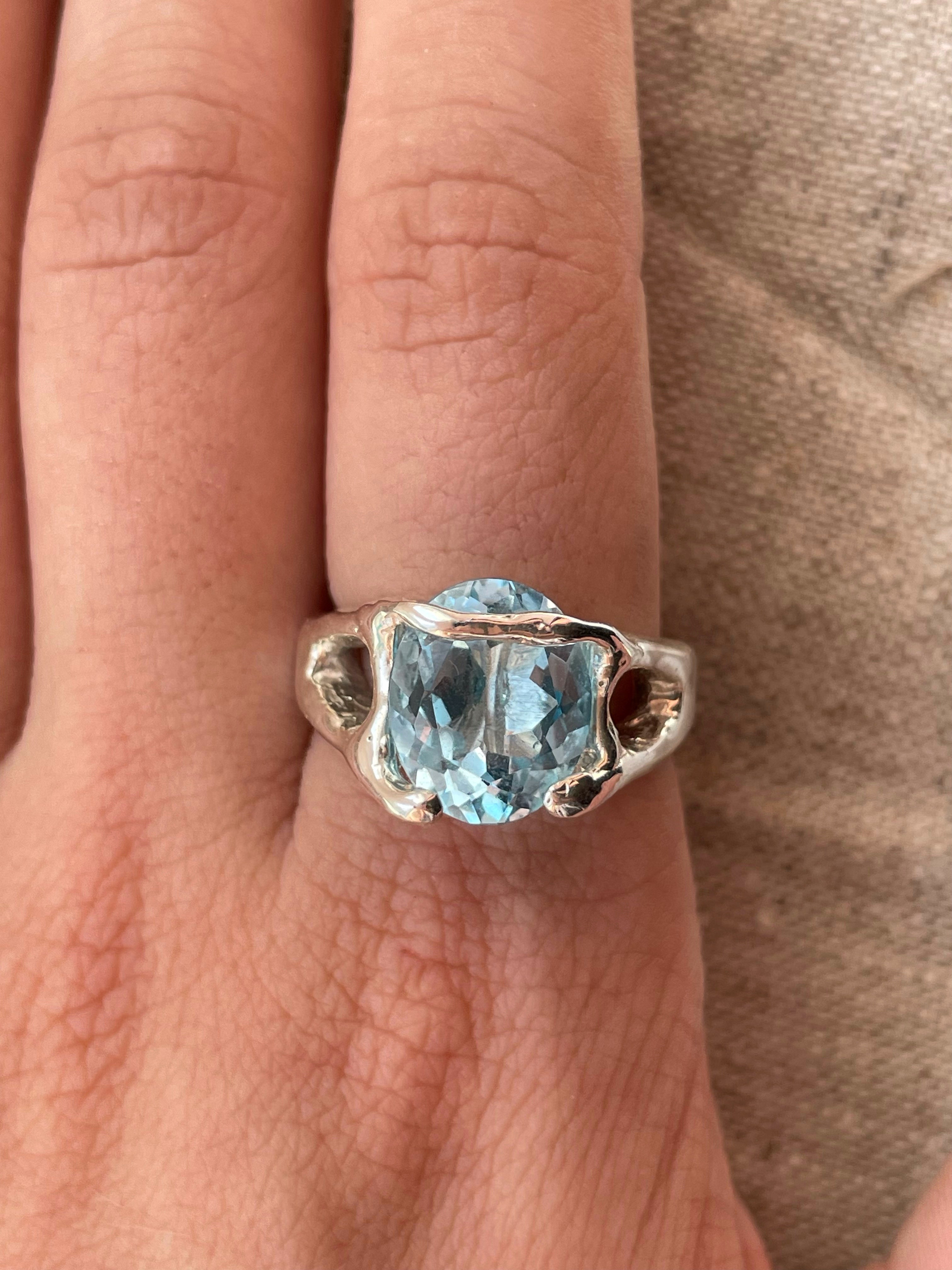 Bespoke silver ring with topaz on finger.