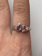 Bespoke silver ring with two pink sapphires on a person's finger.