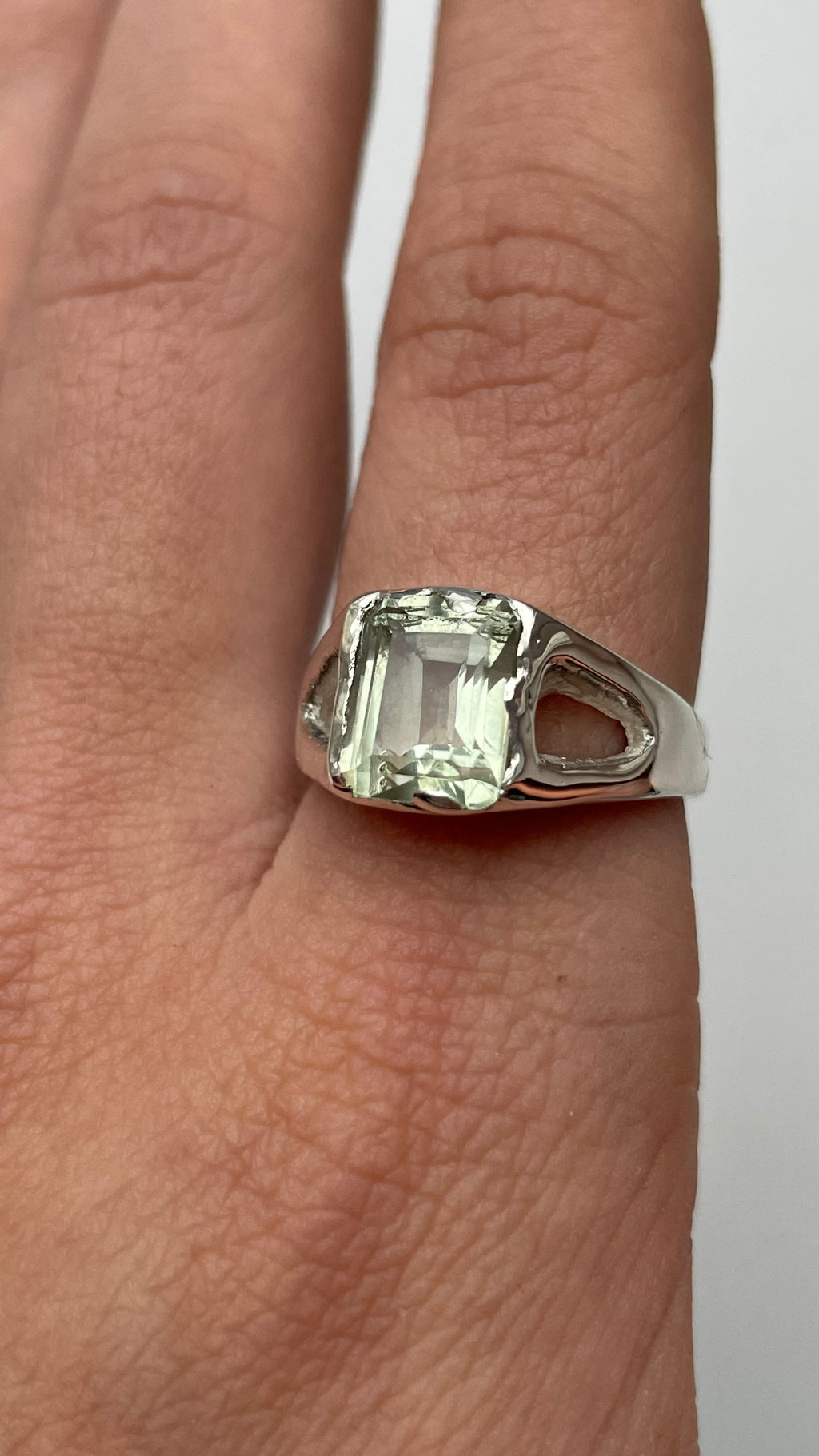 Bespoke silver ring with a green amethyst on a finger 